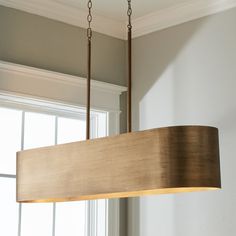 a wooden light fixture hanging from a ceiling in a room with white walls and windows