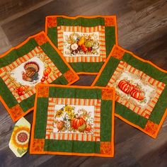 four quilted placemats with pumpkins and sunflowers on them sitting on a wood floor