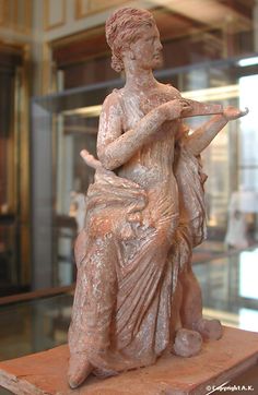 a statue of a woman sitting on top of a wooden table next to a glass case