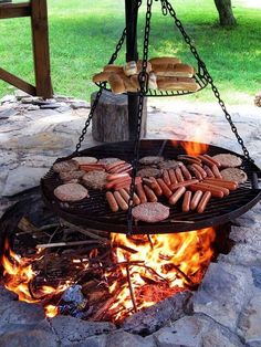 hot dogs and hamburgers are being cooked on an open fire pit in the park