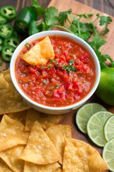 a bowl of salsa with tortilla chips and limes