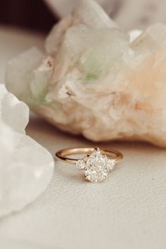 an engagement ring sitting on top of a white table next to some rocks and crystals