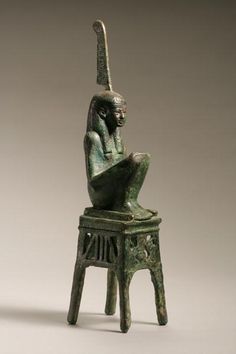 an ancient statue sitting on top of a stool