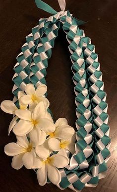 a wreath made out of blue and white ribbon with flowers on it, sitting on a table