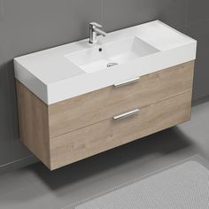 a white sink sitting next to a wooden cabinet on top of a gray tiled floor