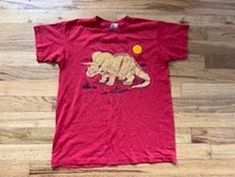 Vintage triceratops t-shirt. Fits like an XS. Check measurements below for most accurate sizing.  Cracking to decal. Worn. Single stitch. Brand is Hanes 50/50. Made in the USA. 50% polyester. 50% cotton.  -- Measurements --  Chest: 17 inches  Length: 21 inches  Sleeve: 9.5 inches Shirt Fits, 50 50, Gender Neutral, Adult Outfits, T-shirt, Tops & Tees, Top Outfits, T Shirts, Purses And Bags