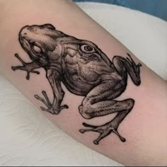 a black and white frog tattoo on the arm