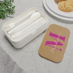 two plastic containers with spoons and forks in them on a table next to cookies