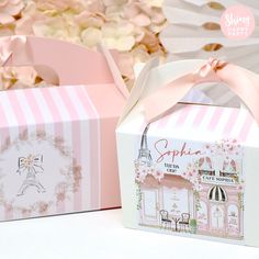 two pink boxes with bows on them sitting next to each other in front of flowers