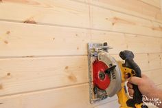 a person using a power drill to attach a piece of wood on the side of a wall