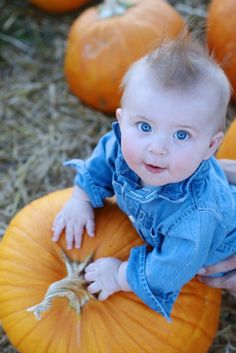 a baby sitting on top of a pumpkin