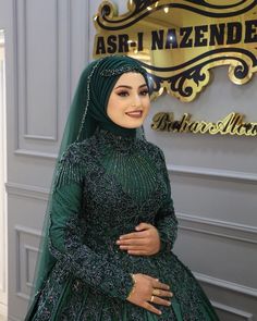 a woman in a green wedding dress standing next to a gold and black sign that says asr - naznd