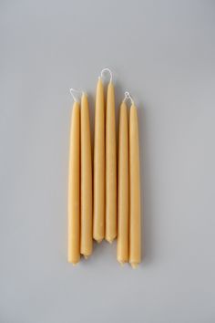 four yellow candles sitting next to each other on a gray surface with one candle in the middle