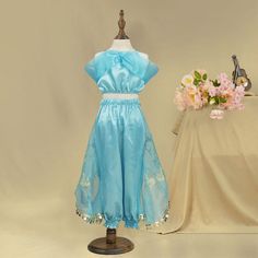 a dress on a mannequin next to a vase with flowers