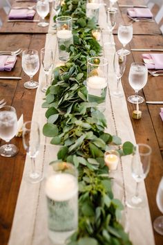 a long table with candles and greenery on it