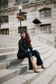 a woman sitting on some steps with her legs crossed and wearing high heeled shoes