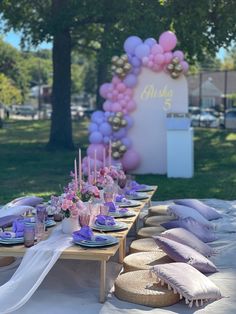 a table set up with plates, napkins and candles for an outdoor birthday party