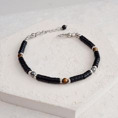 Black Stone Bracelet, Onyx, Tigers Eye and Hematite Protection Healing Crystal Bracelet. This great everyday stackable slim bracelet is made with Black Onyx heishi beads, which are separated by Sterling Silver spacers and Tiger's Eye and Hematite beads. Fastened with our signature Stainless Steel hook and adjustable chain fastening, making a luxurious strong and wearable and waterproof bracelet for men or women, that you won't want to take off.  Onyx - Is a stone of protection, strength and focu Minimalist Adjustable Bracelets With Black Beads, Minimalist Hematite Round Bead Jewelry, Minimalist Bracelets With Black Beads, Minimalist Adjustable Black Beads Bracelets, Adjustable Minimalist Hematite Jewelry, Minimalist Bracelets With Spacer Beads, Modern Black Beads Bracelets As Gift, Minimalist Silver Beaded Bracelet With Black Beads, Modern Black Beads Bracelet As Gift