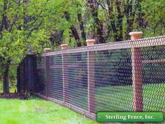 a chain link fence in front of some trees and grass with the words sterling fence, inc