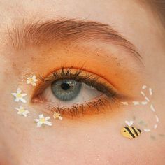 a woman's eye with yellow and white flowers painted on her eyeshade