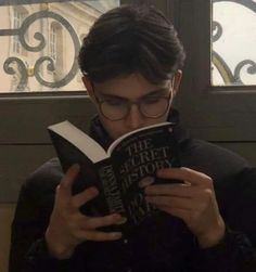 a man reading a book in front of a window