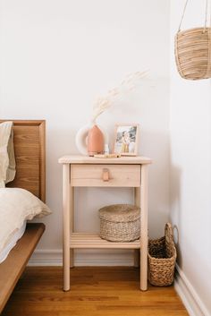 a small wooden table sitting on top of a hard wood floor next to a bed