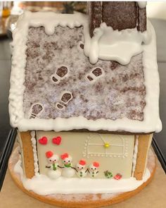 a gingerbread house with white icing and snow on the roof