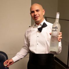 a man in a tuxedo holding a bottle of alcohol