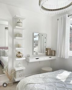 a bedroom with white walls and flooring has a large mirror on the wall above the bed