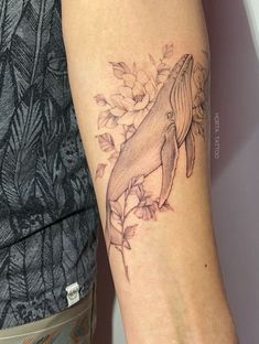 a woman's arm with a tattoo of a humpback whale on it