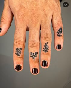 a person's hand with tattoos on it and two fingers in the air,