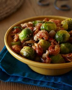 a yellow bowl filled with brussel sprouts on top of a blue napkin