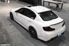 a white car parked in a garage next to a bench