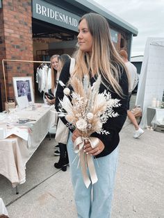 a woman is standing outside with flowers in her hand