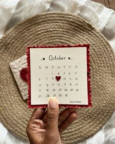 someone holding up a calendar card with the word october on it and a red heart