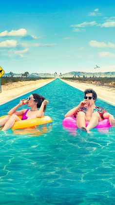 two women sitting on inflatable rafts floating down a long stretch of water