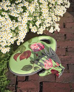 a pair of scissors sitting on top of a green tray next to white daisies