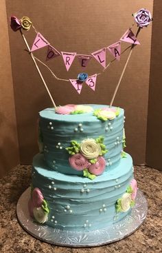 a blue cake with flowers and bunting on top