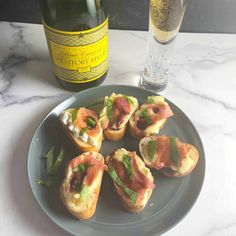 small appetizers on a plate next to a bottle of wine