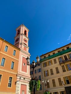 a tall building with a clock on it's side next to other buildings and street lamps