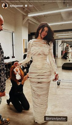 a woman in a white dress standing next to a man holding a stuffed animal on a string