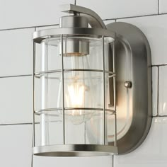 a light fixture mounted on the side of a white brick wall next to a tiled wall