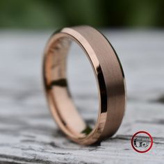 a wedding ring with a red circle in the middle on top of a piece of wood