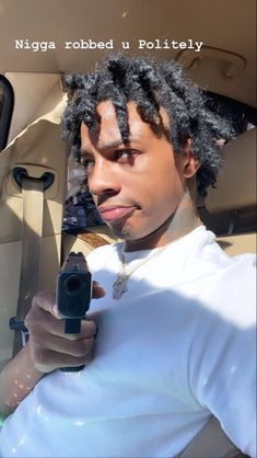 a young man with dreadlocks holding a cell phone in his hand while sitting in the back seat of a car