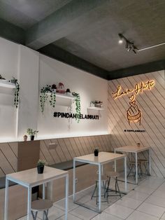 the interior of a restaurant with tables and chairs in front of it, along with plants on the wall