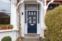 a blue front door on a white house with potted plants in the foreground