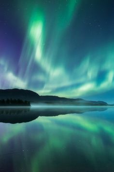 the aurora bore is reflected in water with green and purple lights on it's sides