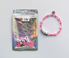 a bag with beads and a bracelet that says lilly next to it on a white surface