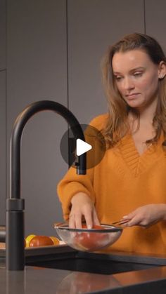 a woman standing in front of a sink with a bowl on the counter next to her