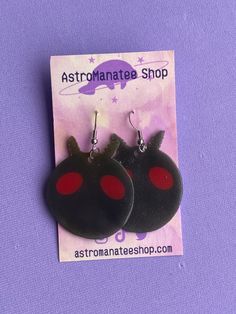 two black and red earrings are sitting on a purple card with the words astromatee shop